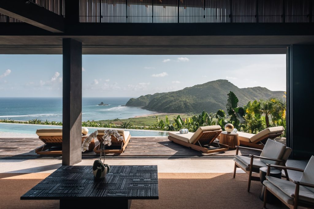 View from living room toward poolside loungers and sea at Villa Layang in Lombok