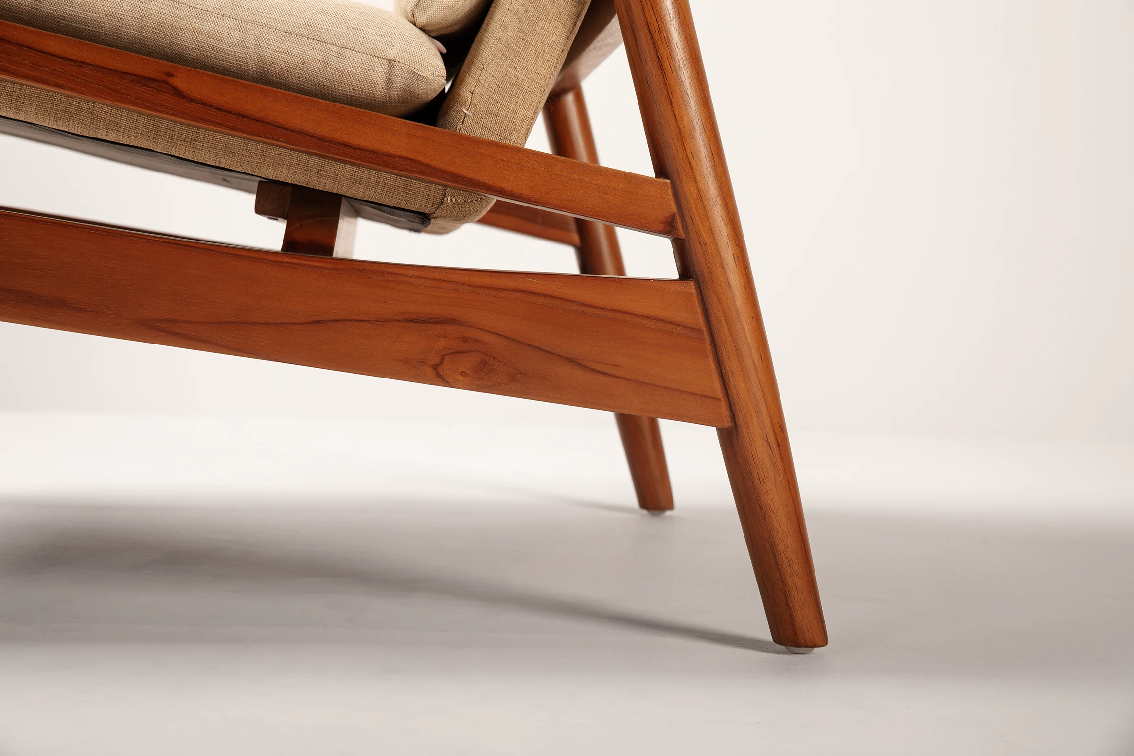 Close up of JENG lounge chair made of teak with fabric upholstered seating from the architectural lines collection
